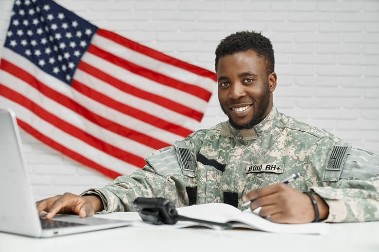 solider smiling on laptop and writing