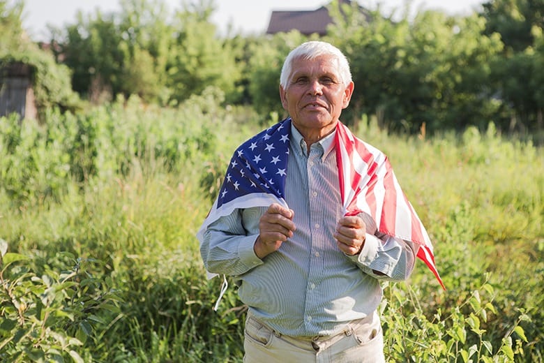 man holding american flag over shoulders