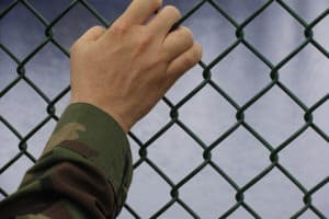 solider holding chain link fence