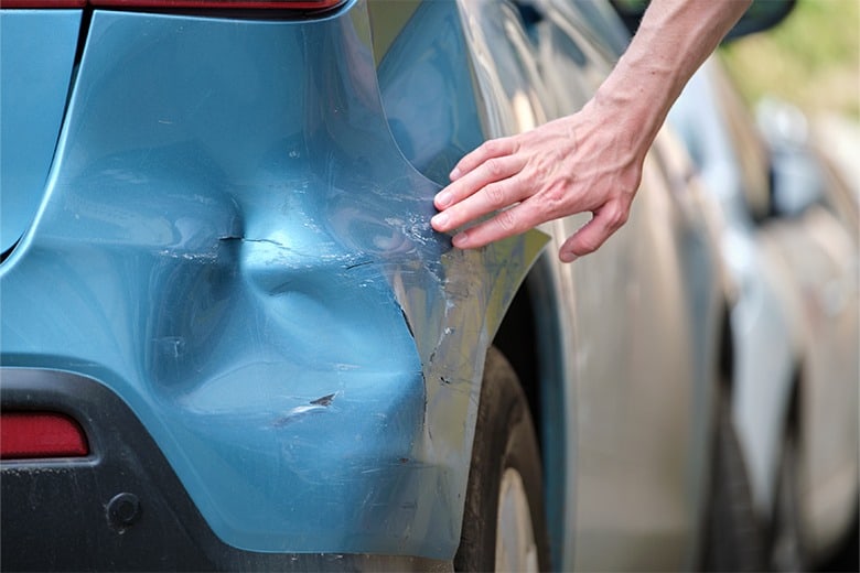 blue-car-with-minor-damage-person-touching-car-evaluating-crash