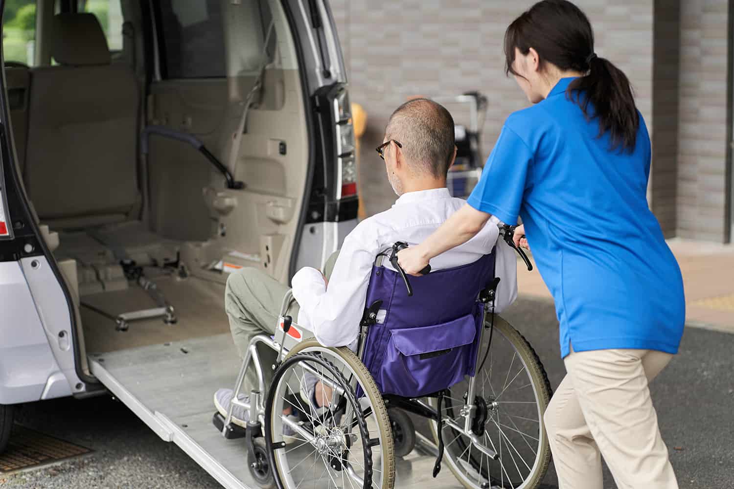 Patient being transported into a handicap accessible van by a caregiver